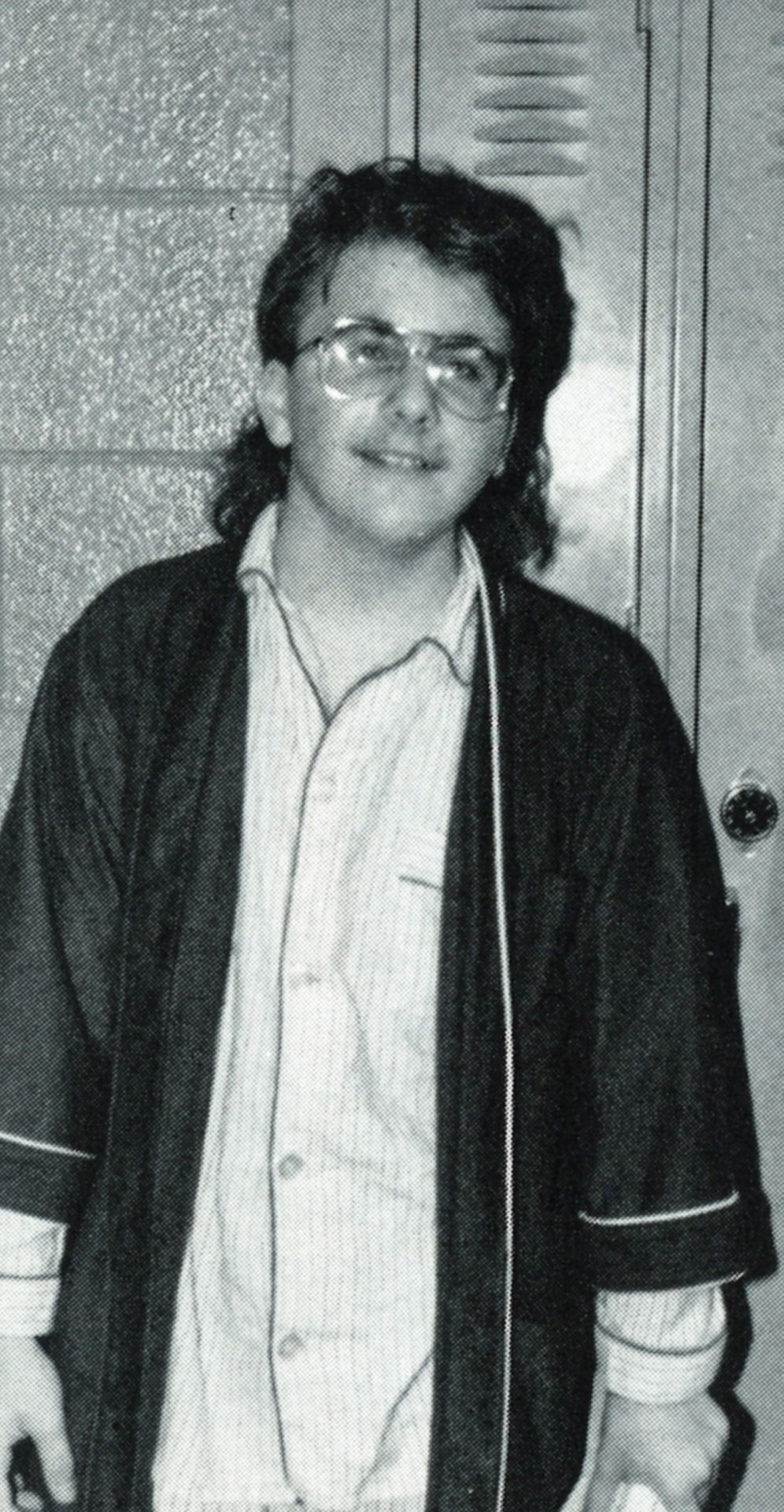 Boy in glasses by lockers, in pajamas and a robe for a dress up day