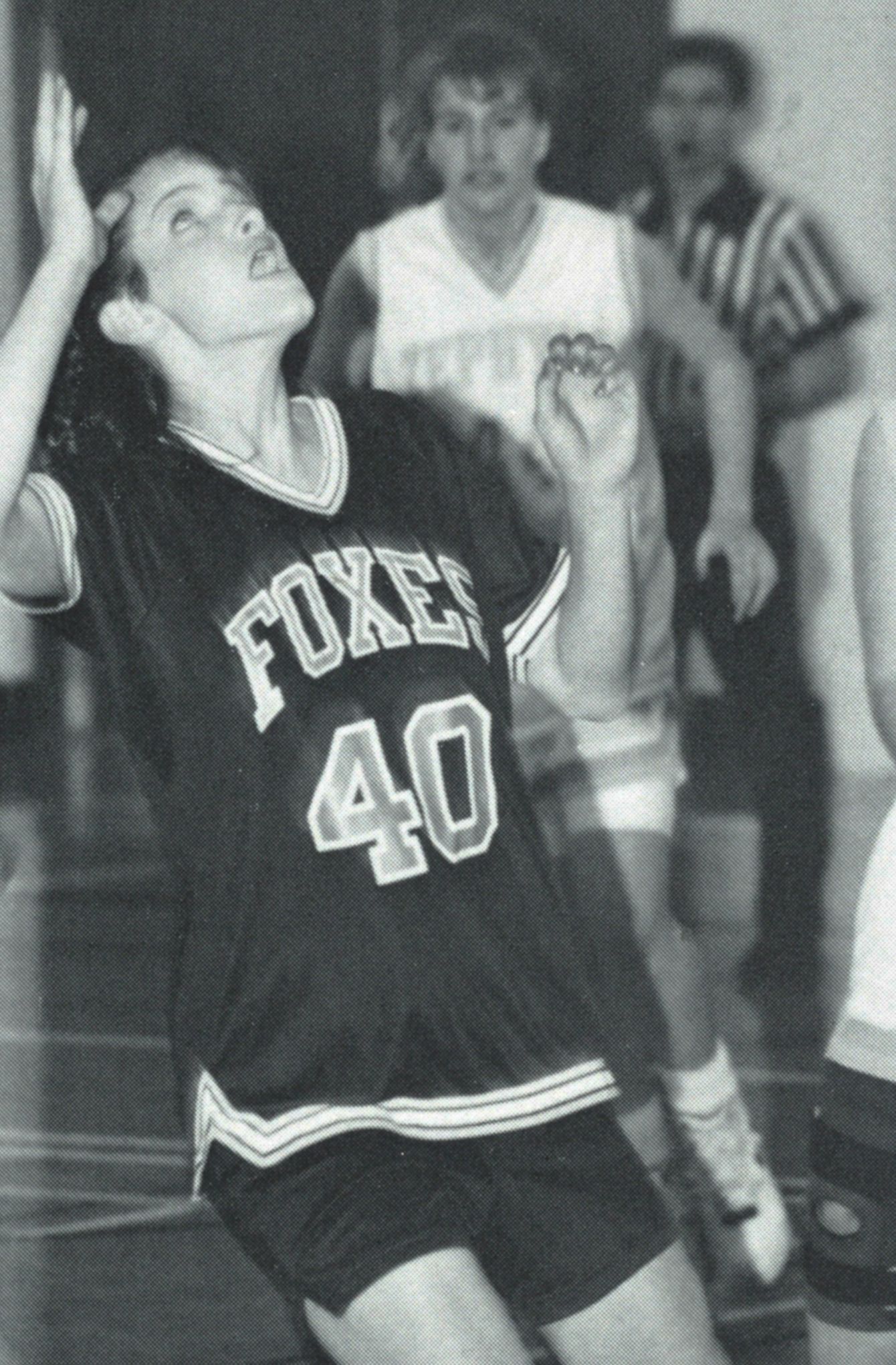 Female basketball player on the court looking up at the ball, poised for action