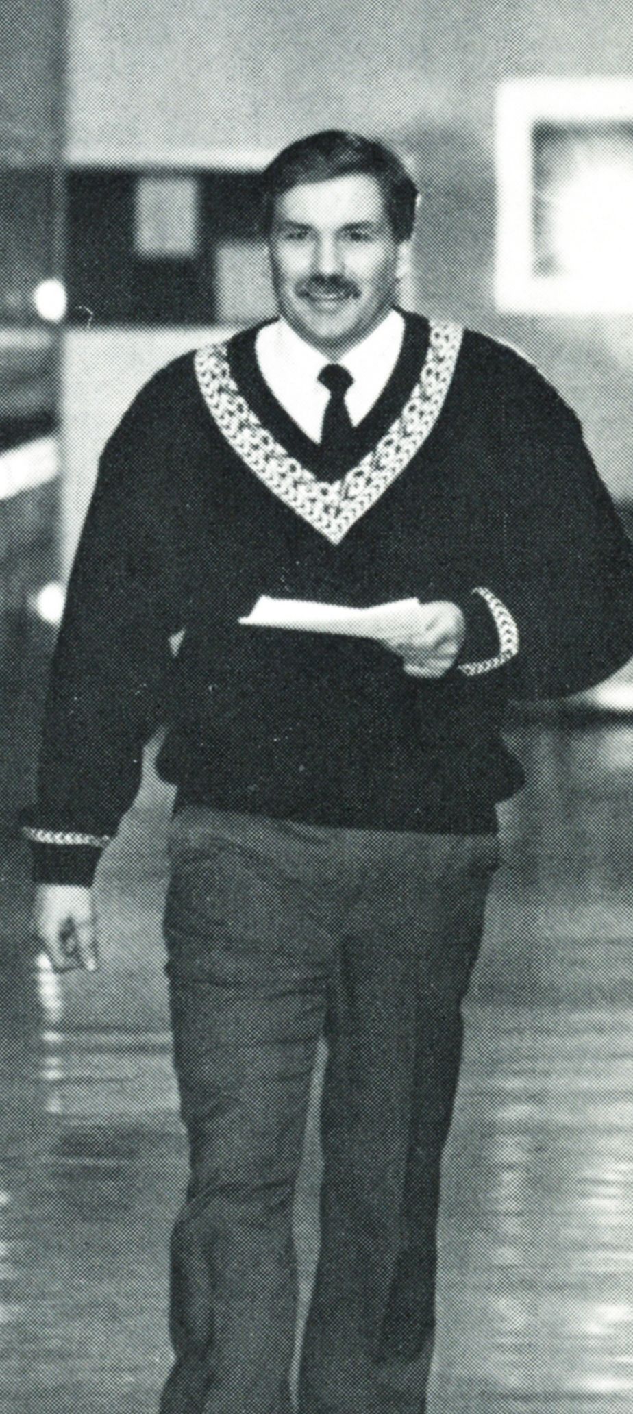 Mr. Hartwig in a v-neck sweater, walking through school