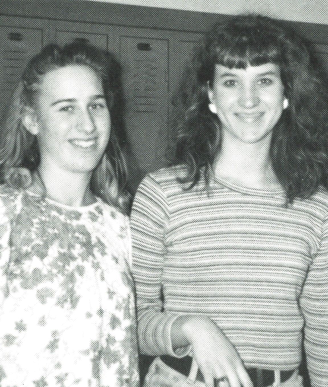Two smiling girls standing next to each other by the lockers