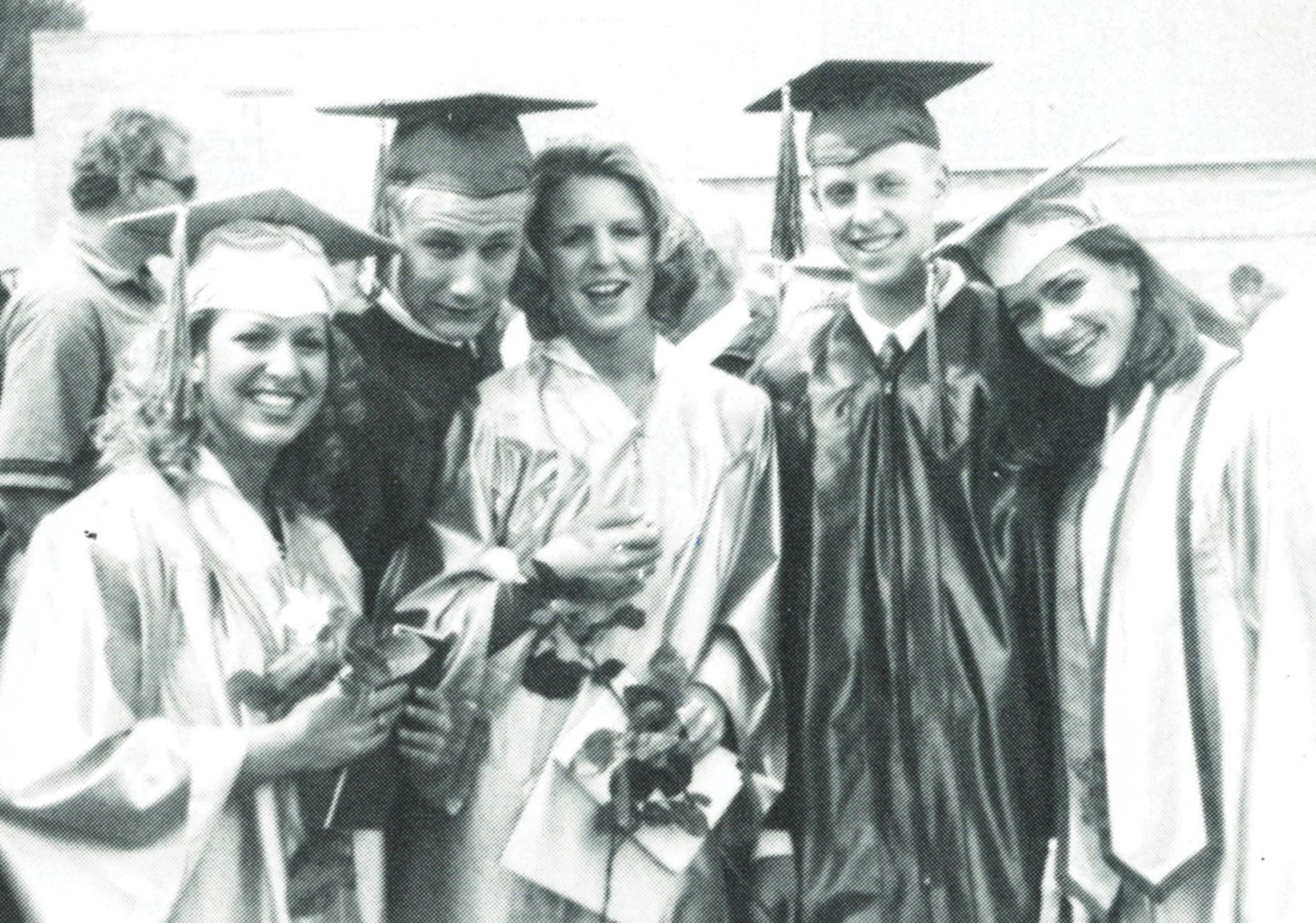 Three girls and two boys in their caps and gowns at graduation