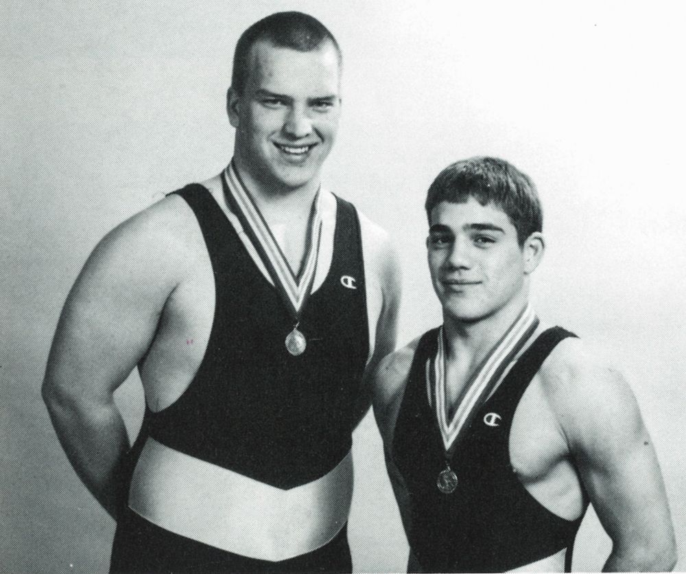 Two wrestlers in their singlets, wearing metals