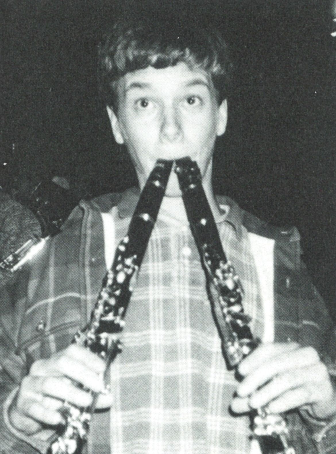 Guy with two clarinets in his mouth. One is held in each hand.