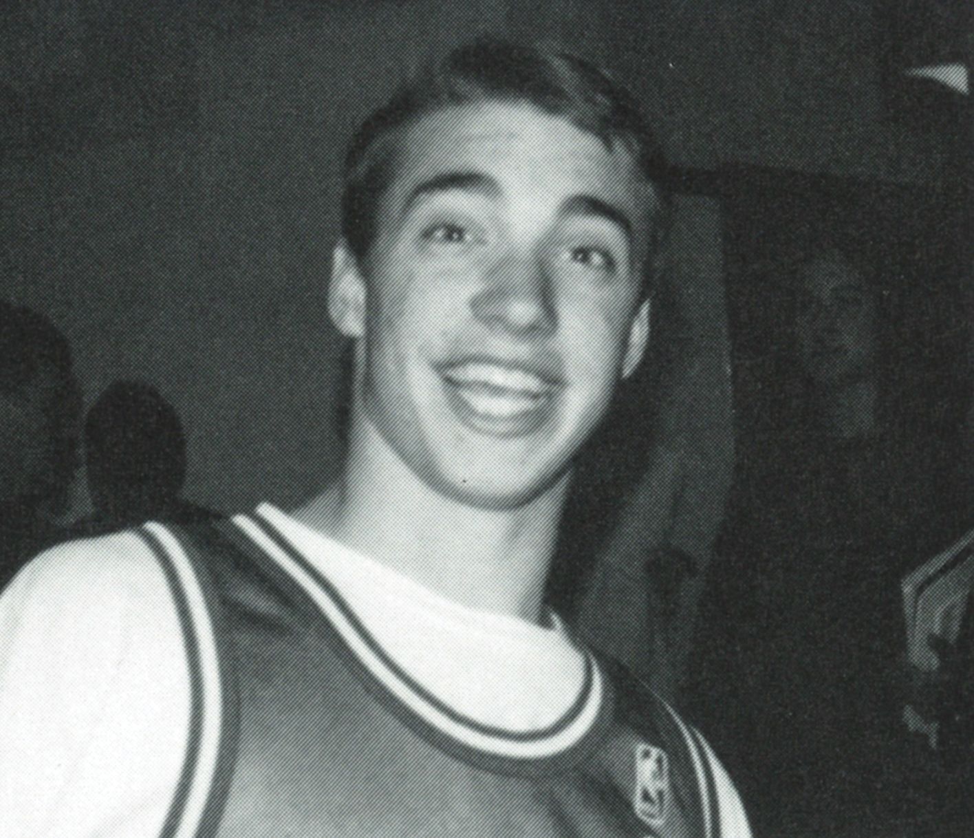 Looking up at a smiling boy in basketball jersey