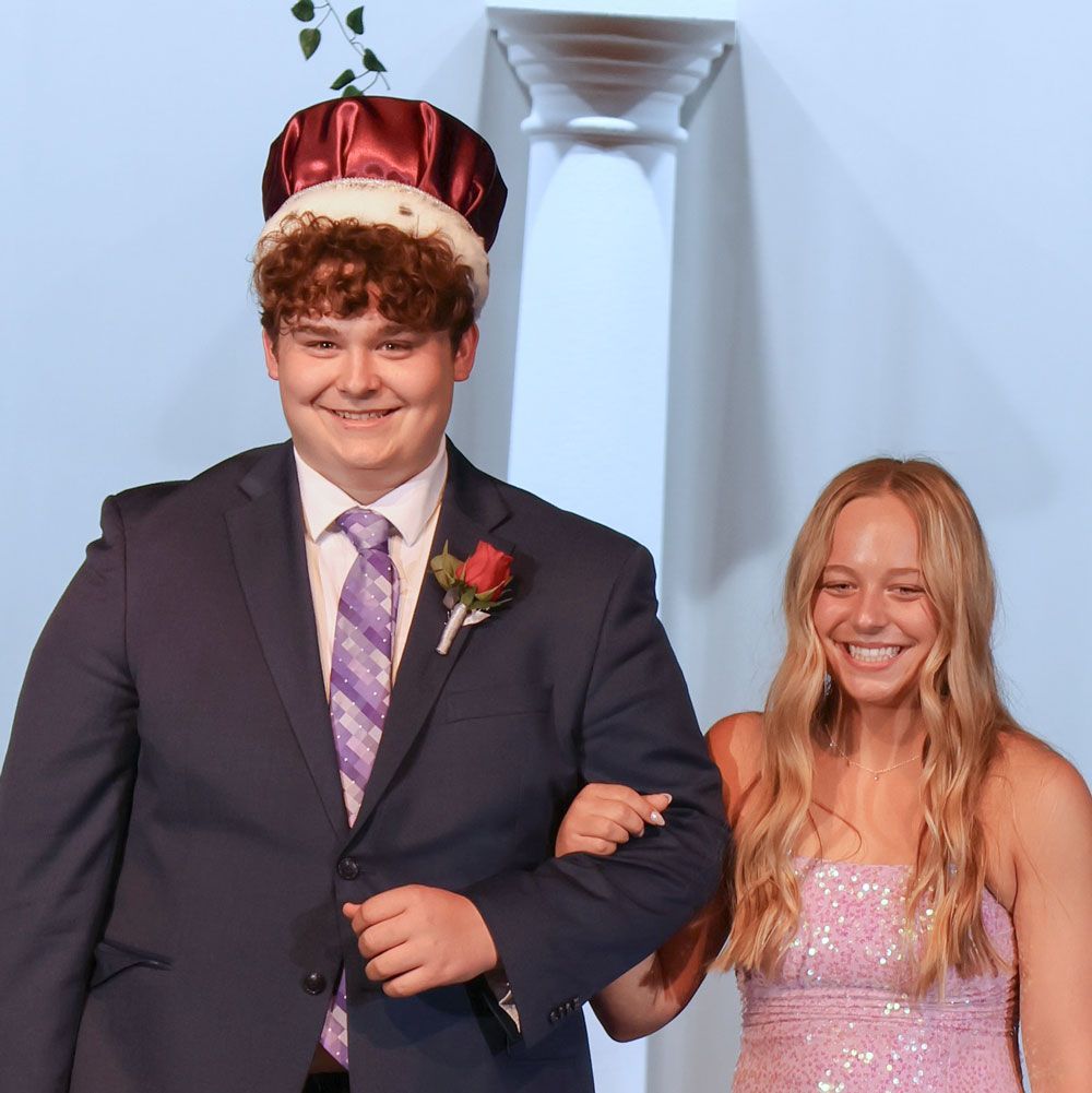 Smiling prom king (wearing his crown) and queen