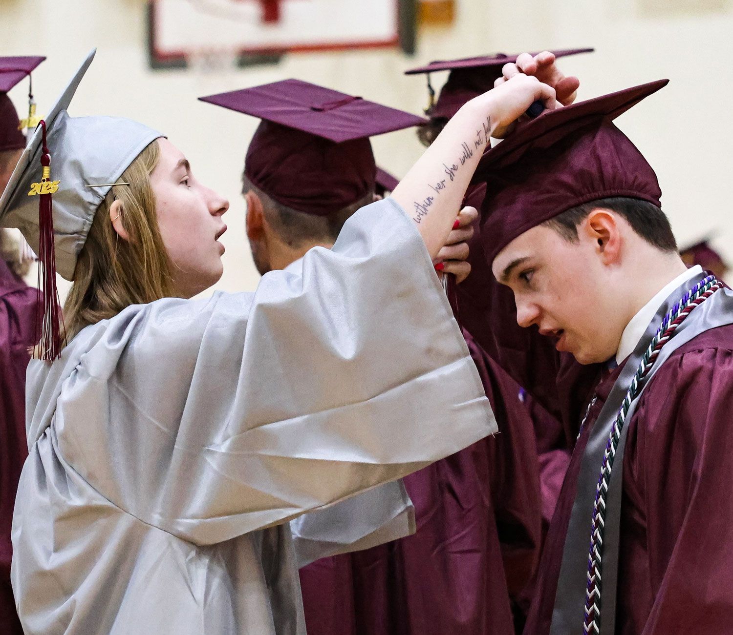 Female student putting mortarboard on male student's head