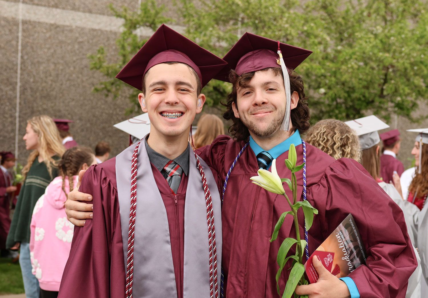Two smiling male students, outside, after ceremony