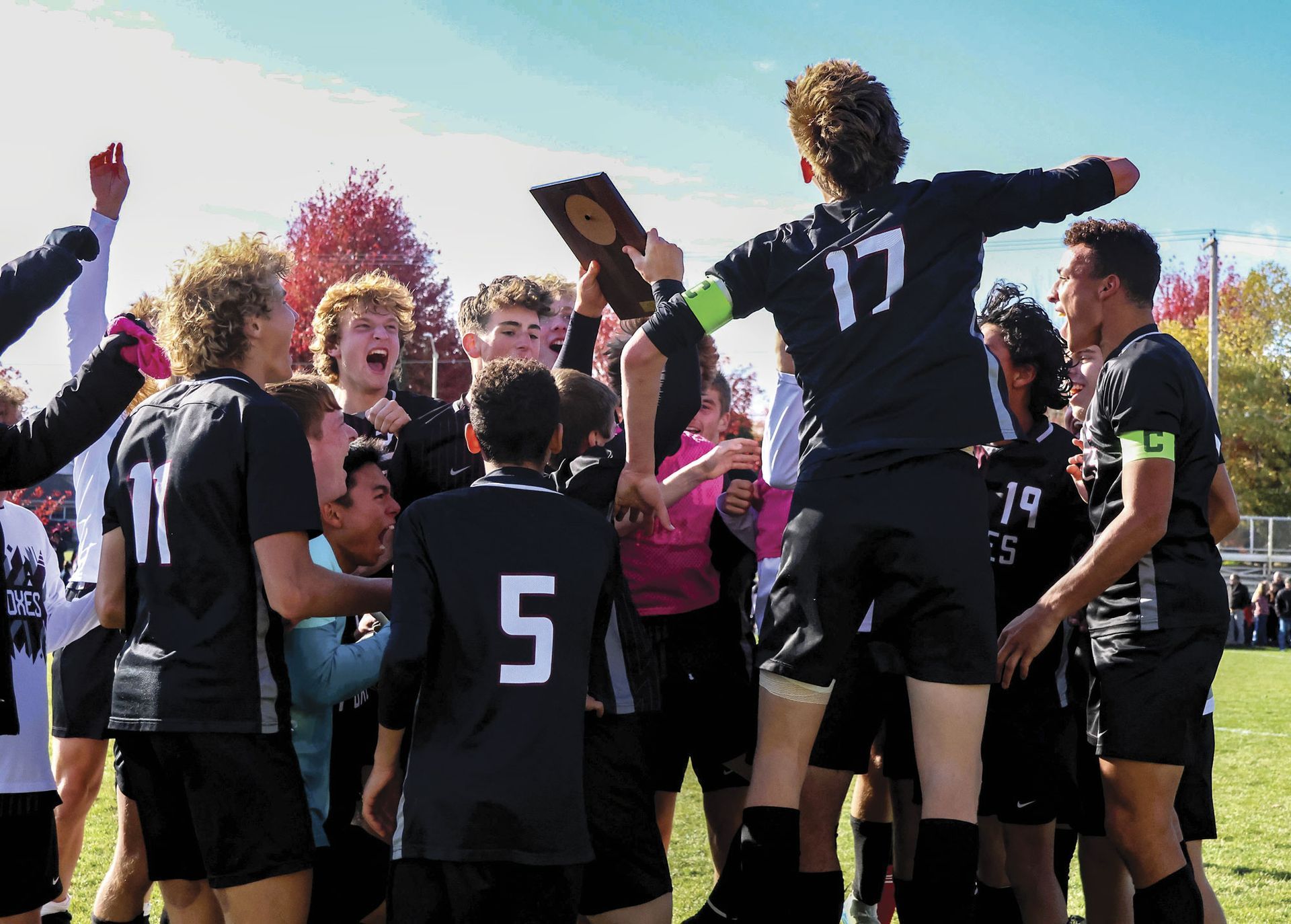 Boys soccer team celebrating after receiving the plaque for Conference Title.