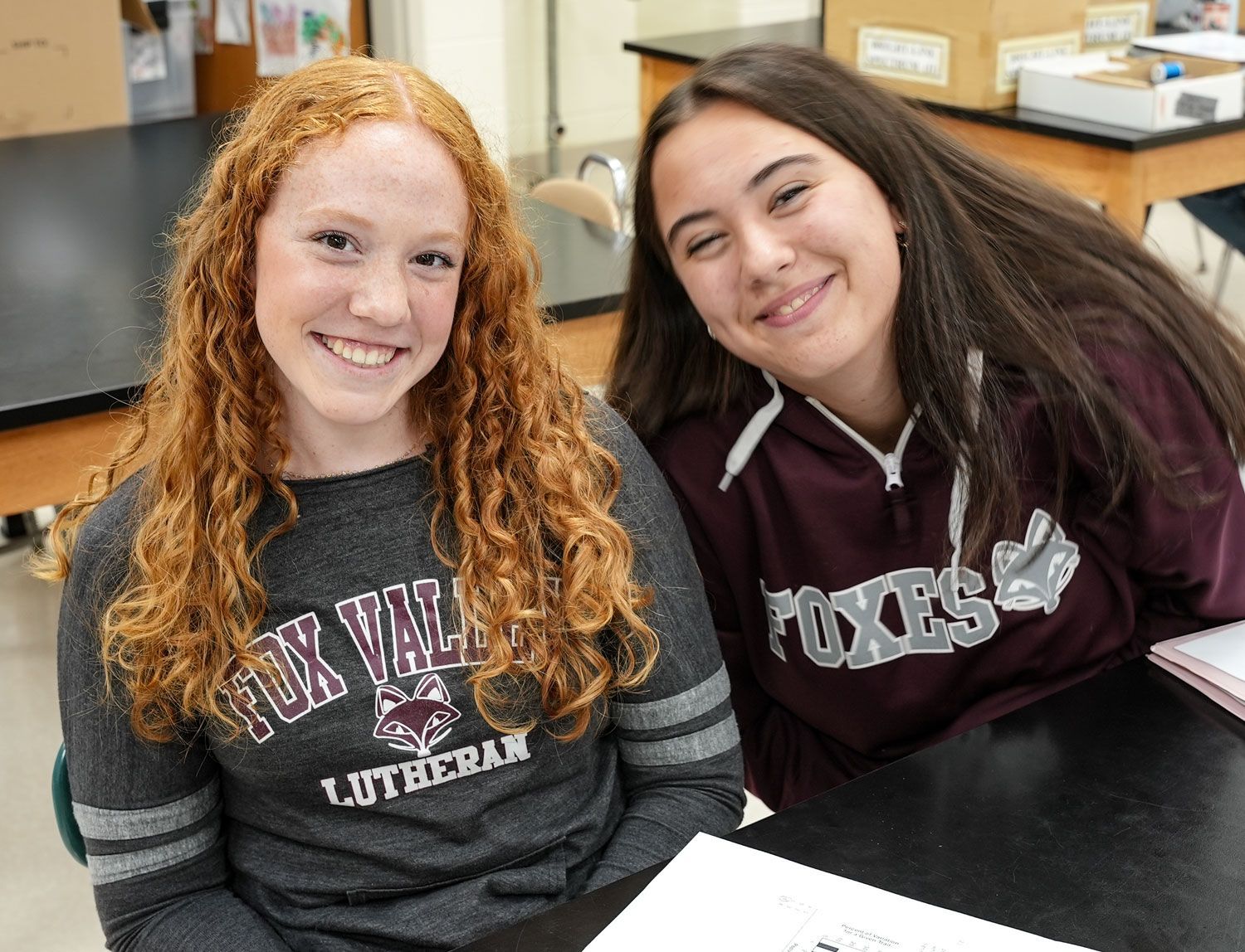 Two smiling FVL female students at a science lab table, looking at the camera