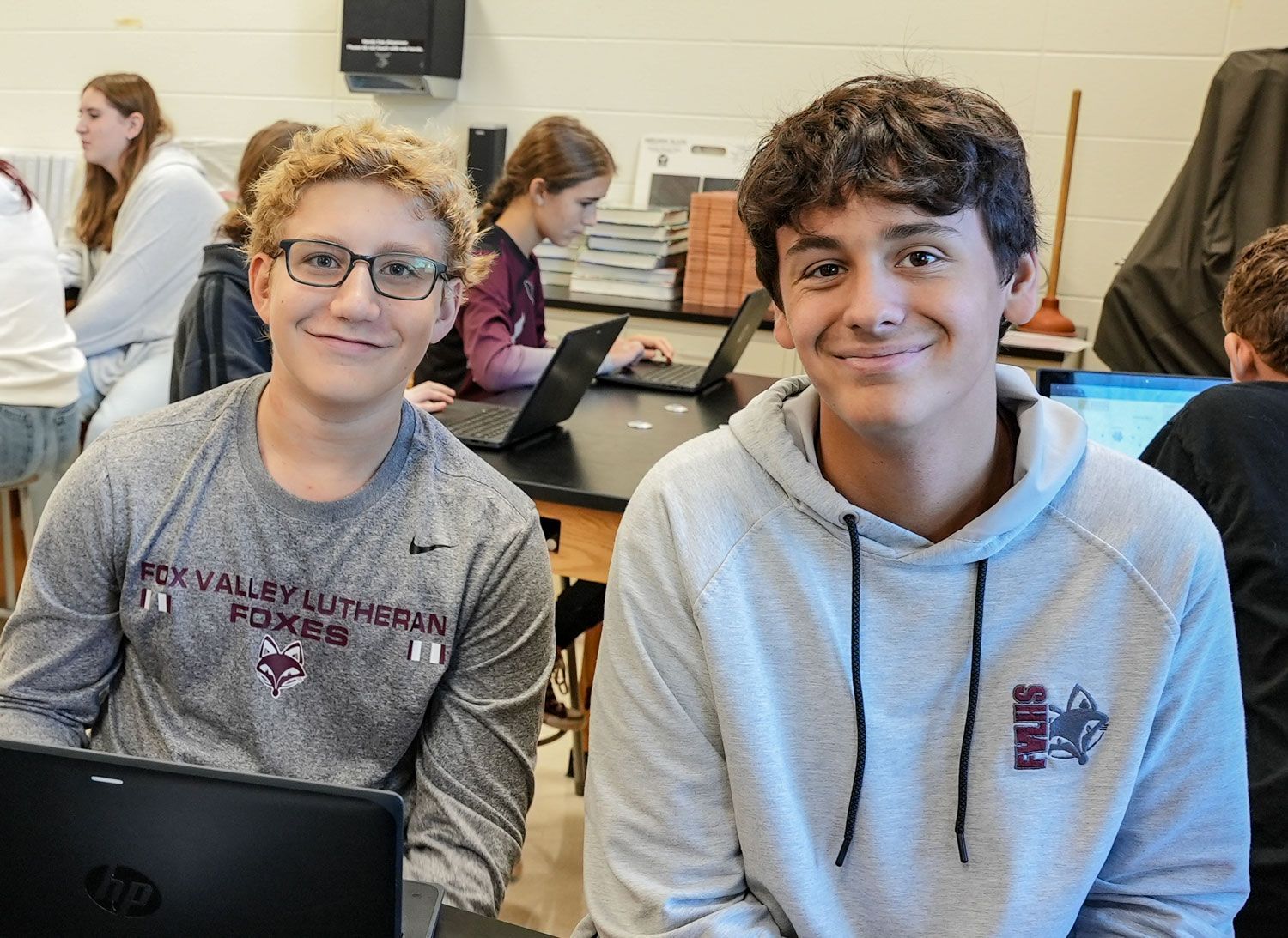 Two smiling male students at a science lab table with their laptops