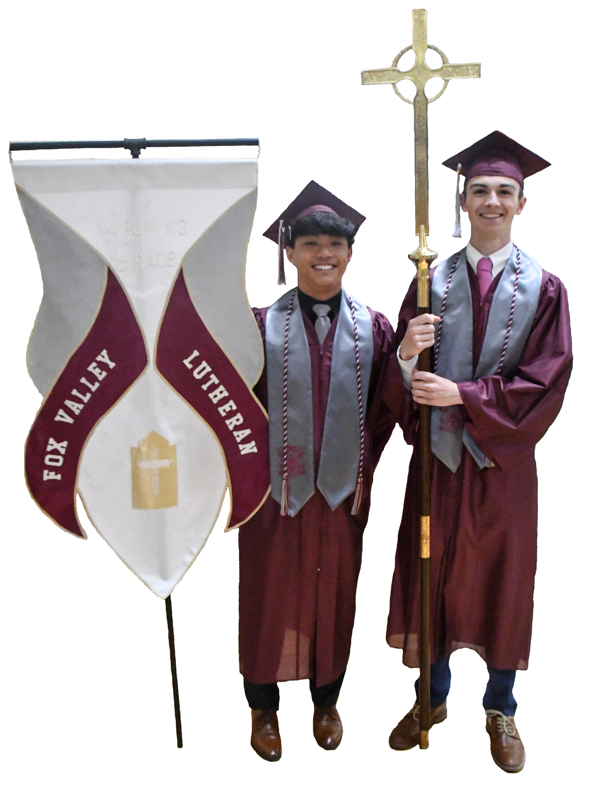 Two smiling guys holding the FVL banner and the cross for graduation