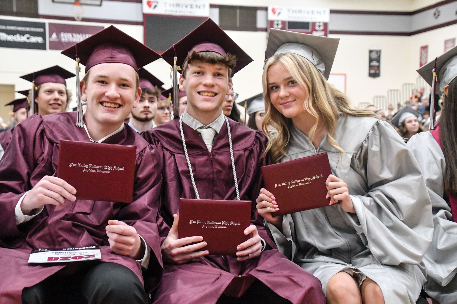 Smiling guys and girl, in their seats, after receiving their diplomas