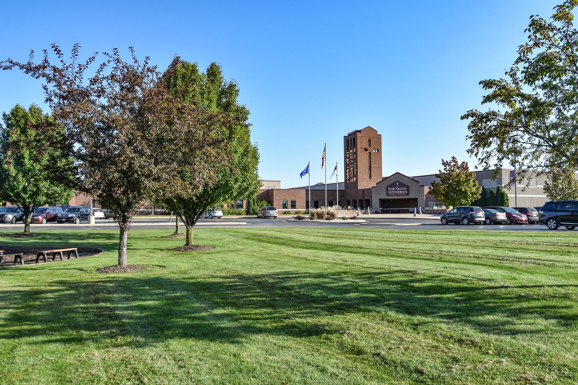 Tower entrance of the school. Sky is a beautiful blue. Grass is green. Trees are in the foreground on the left