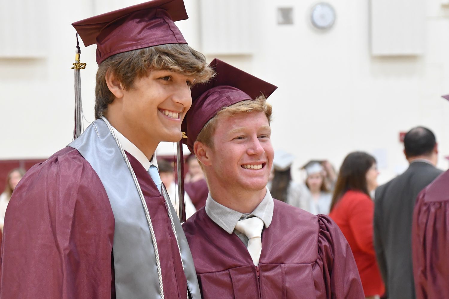 Side view of two guys smiling for a camera in front of them.