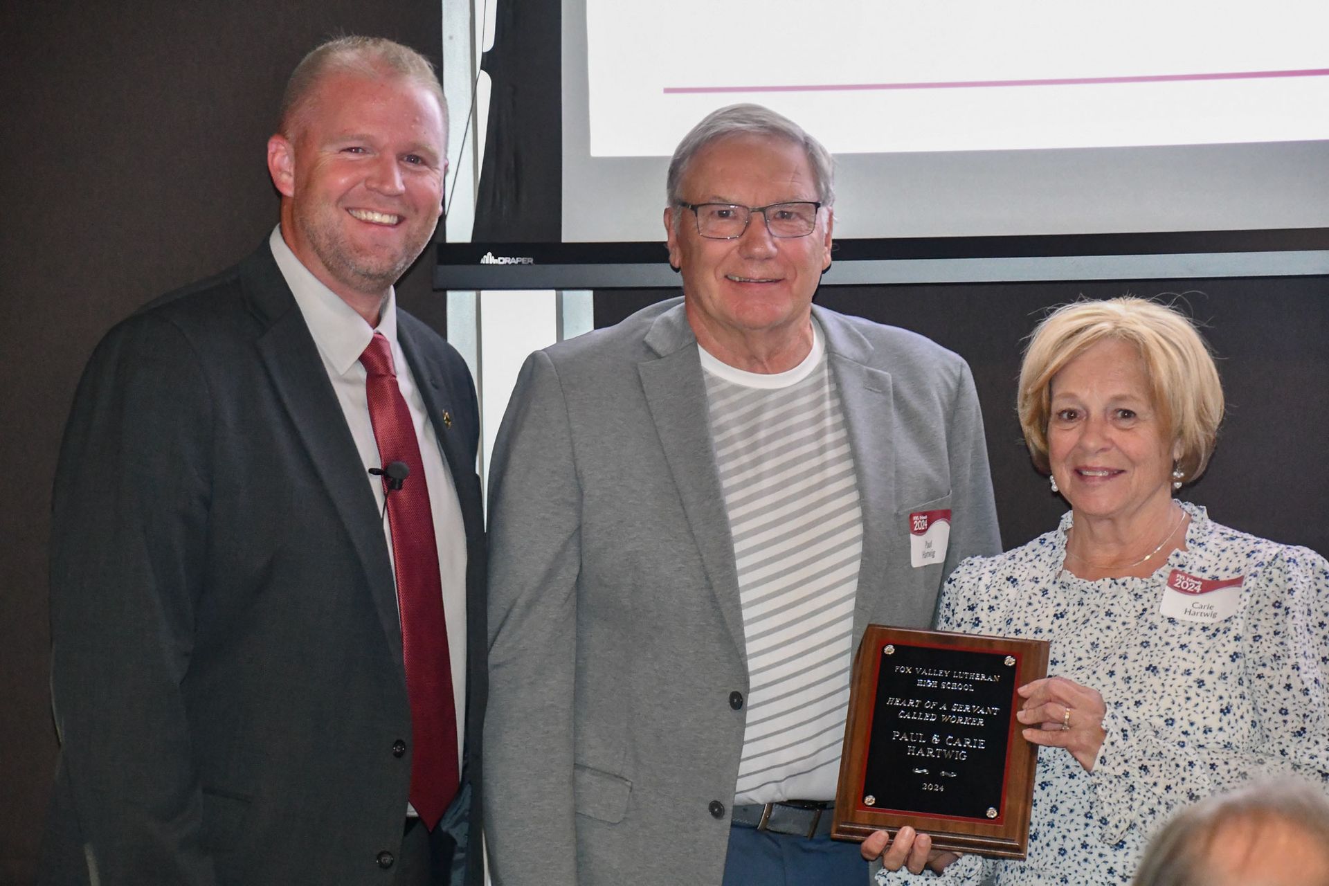 President Loberger smiling and standing by a happy Rev. Ron Ash who is holding up his Heart of a Servant plaque