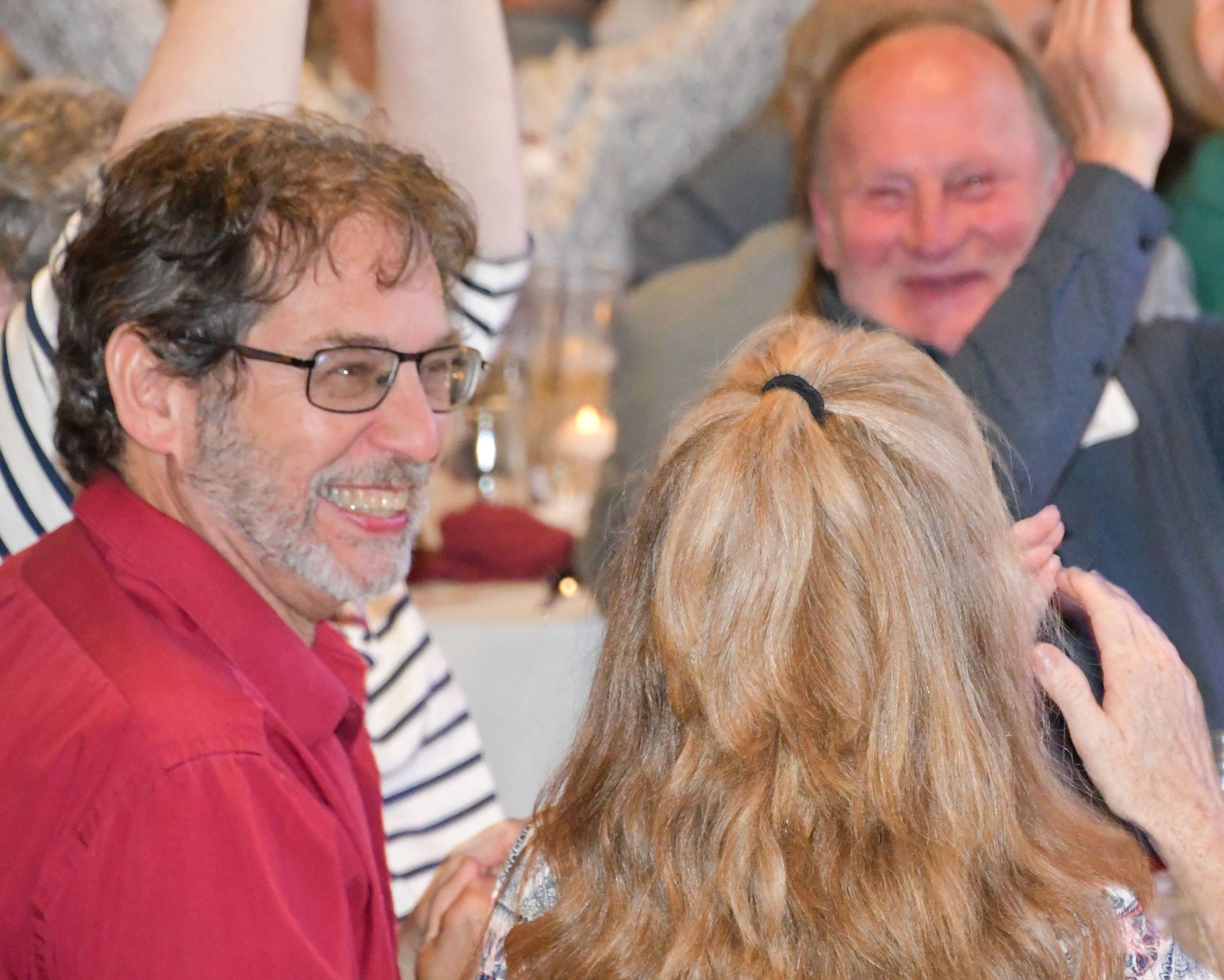 Two happy women standing by a table, in conversation