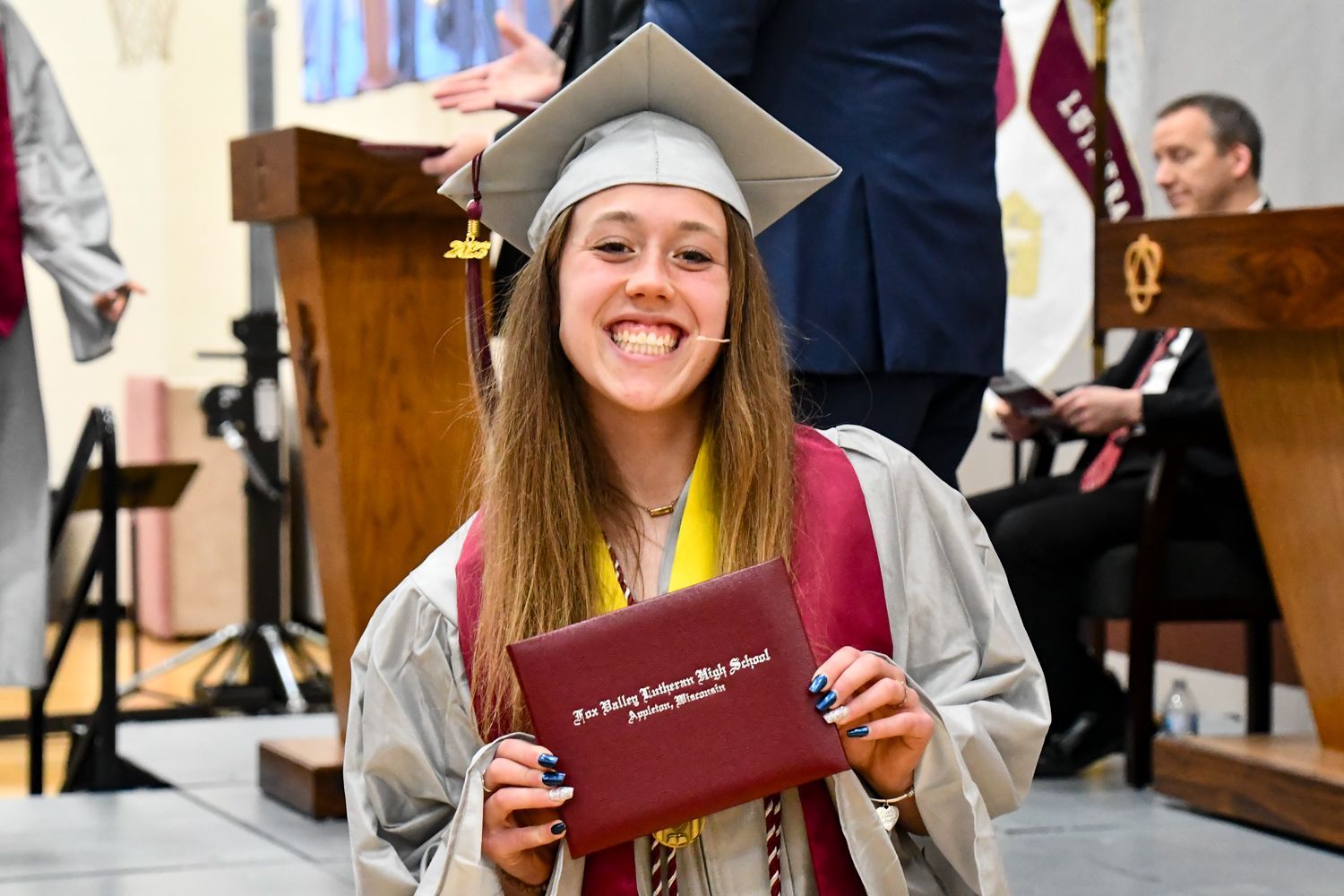 Smiling females student, showing her diploma as she walks off the stage
