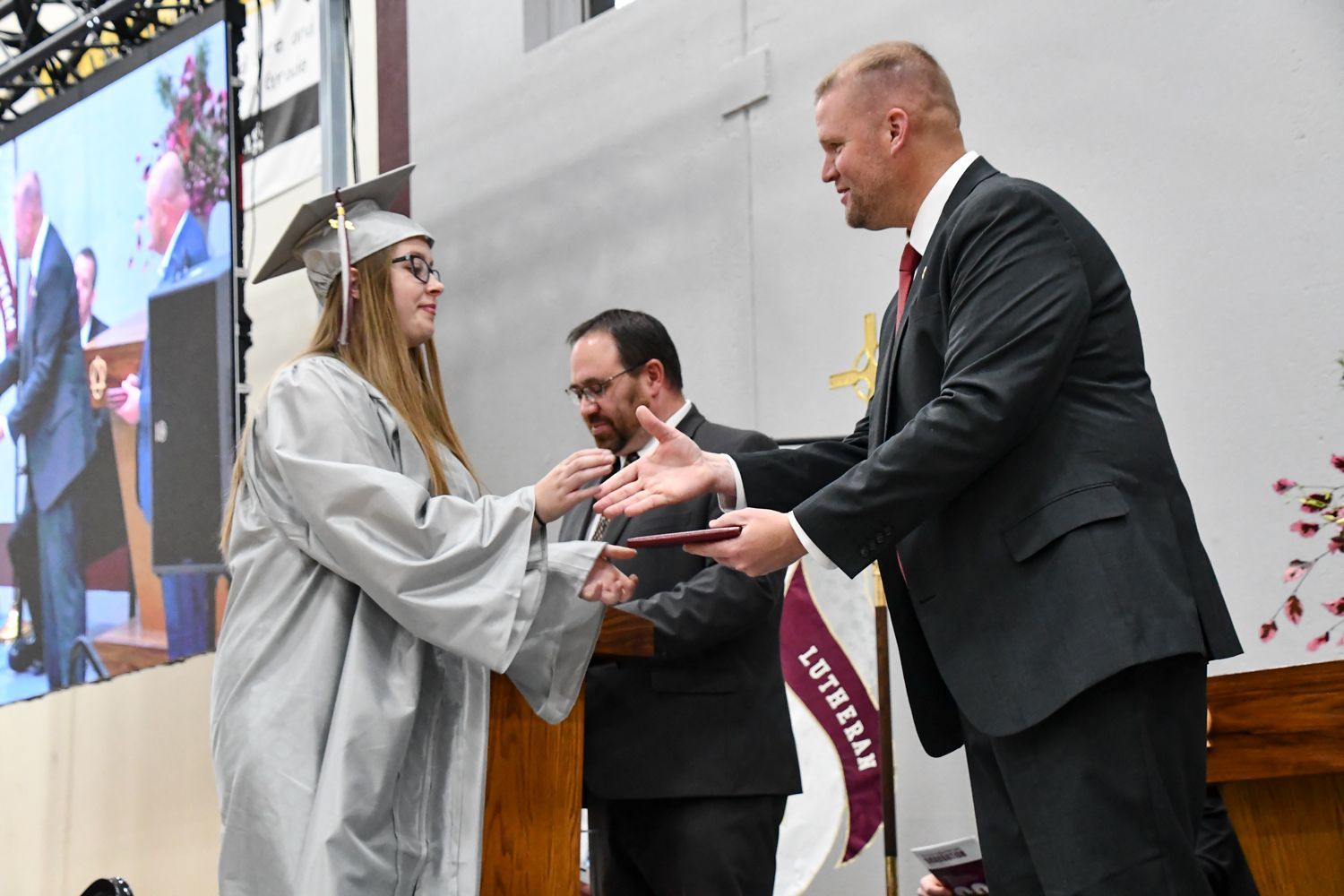 President Loberger shaking the hand of a female student, as he hands her a diploma