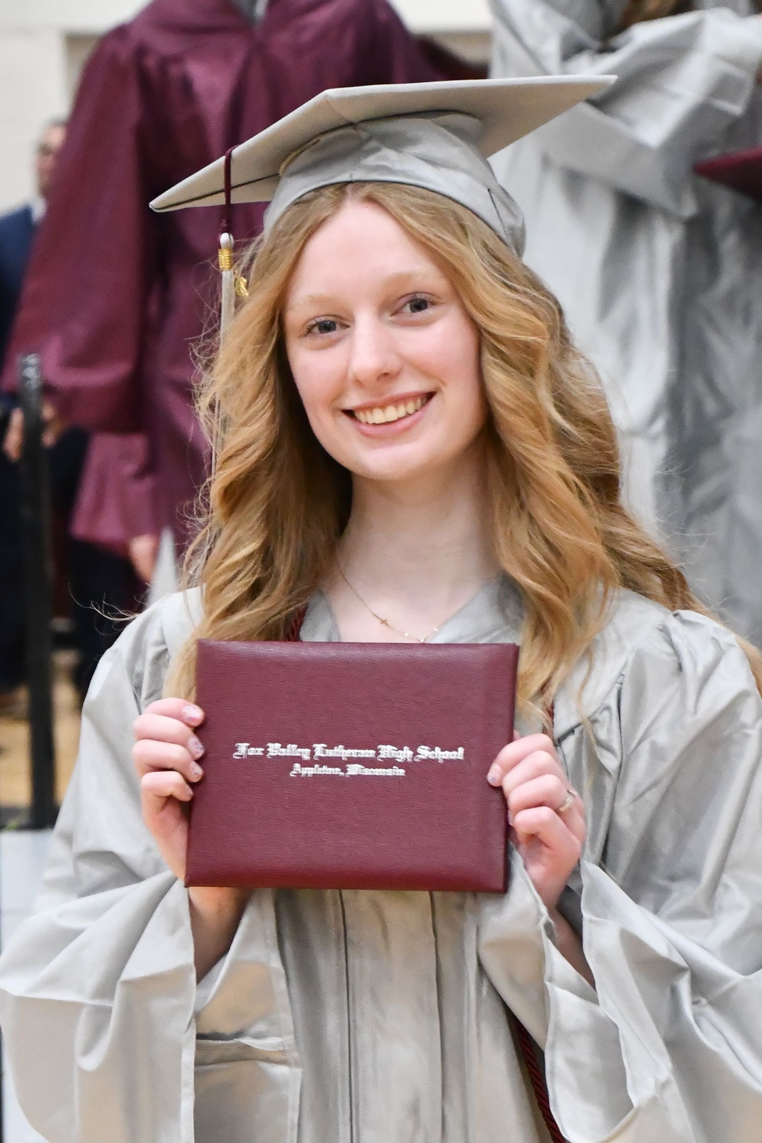 Smiling girl holding up her diploma after coming off stage