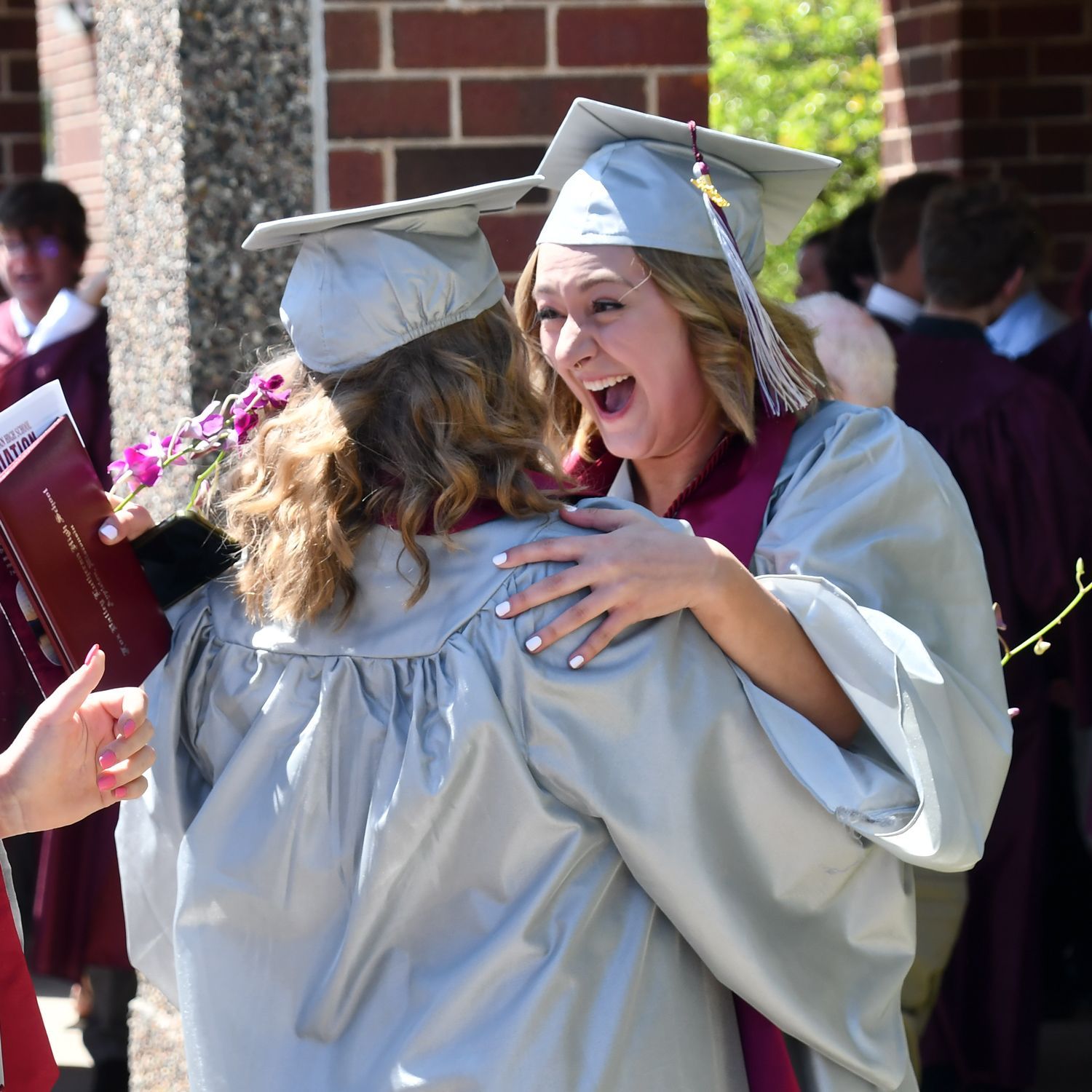 Two laughing girls, giving each other a hug, outside, after the ceremony