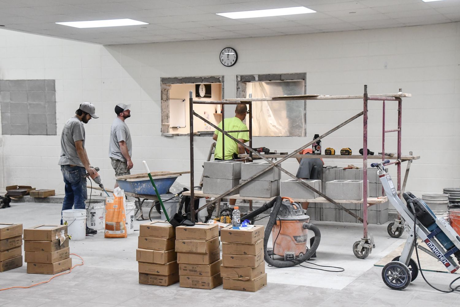 Brick work being done on windows, with bricks, tools, and supplies in the area as well