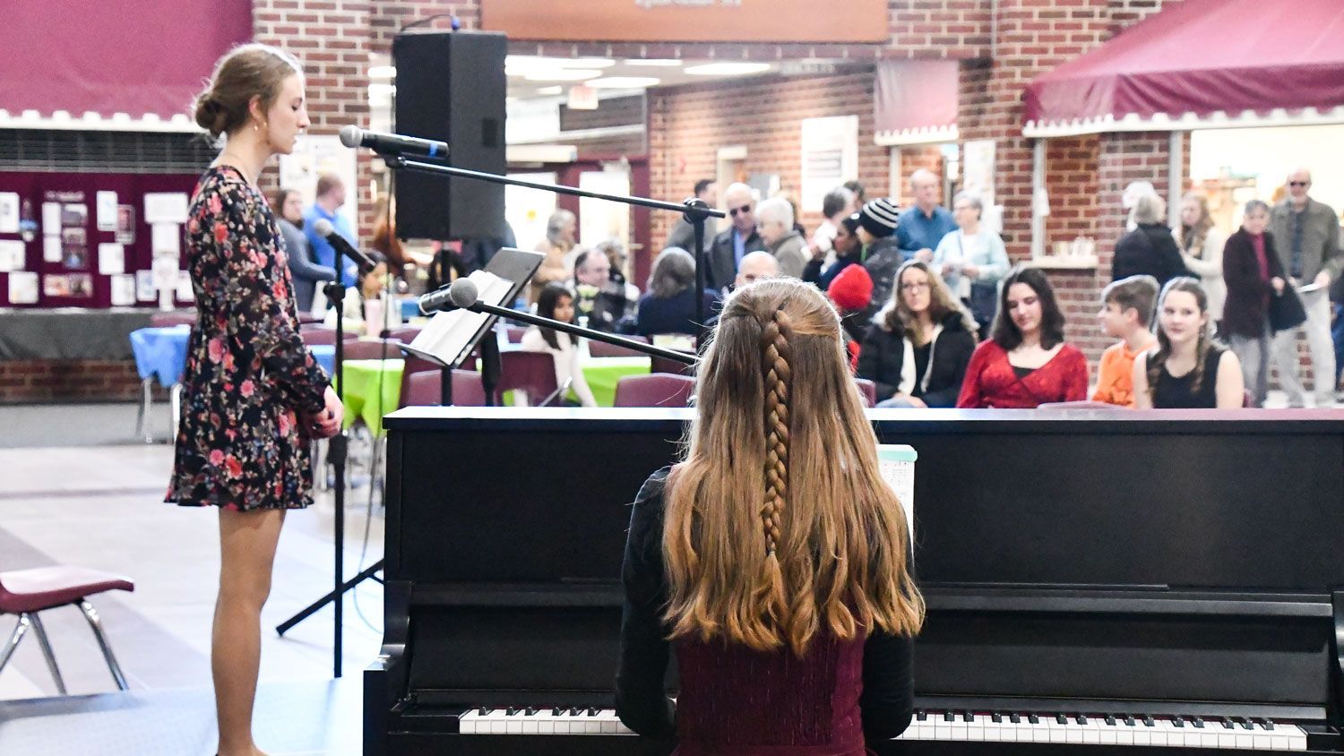 Girl singing in Commons with another girl playing the piano