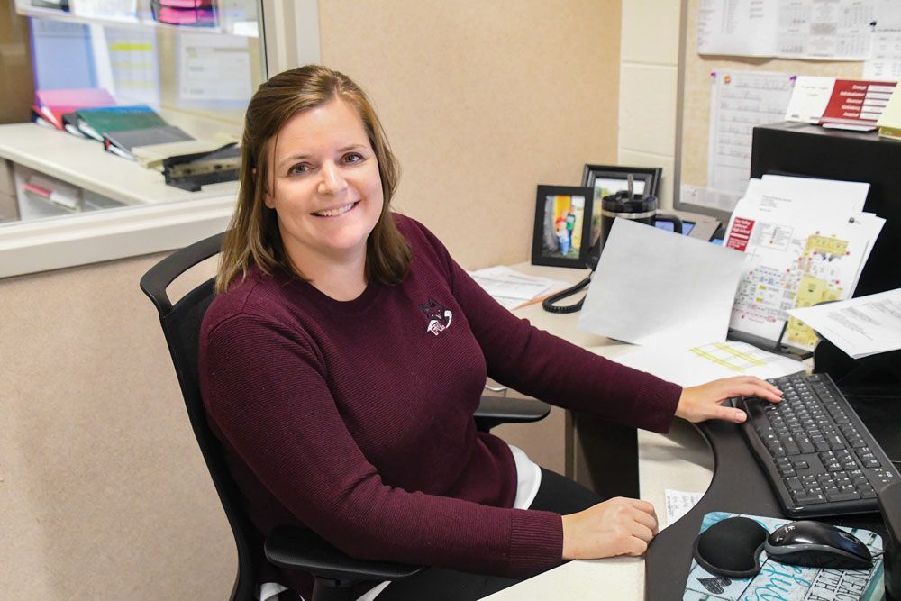 Amanda Voight at her desk in the Guidance Office, smiling at the camera.