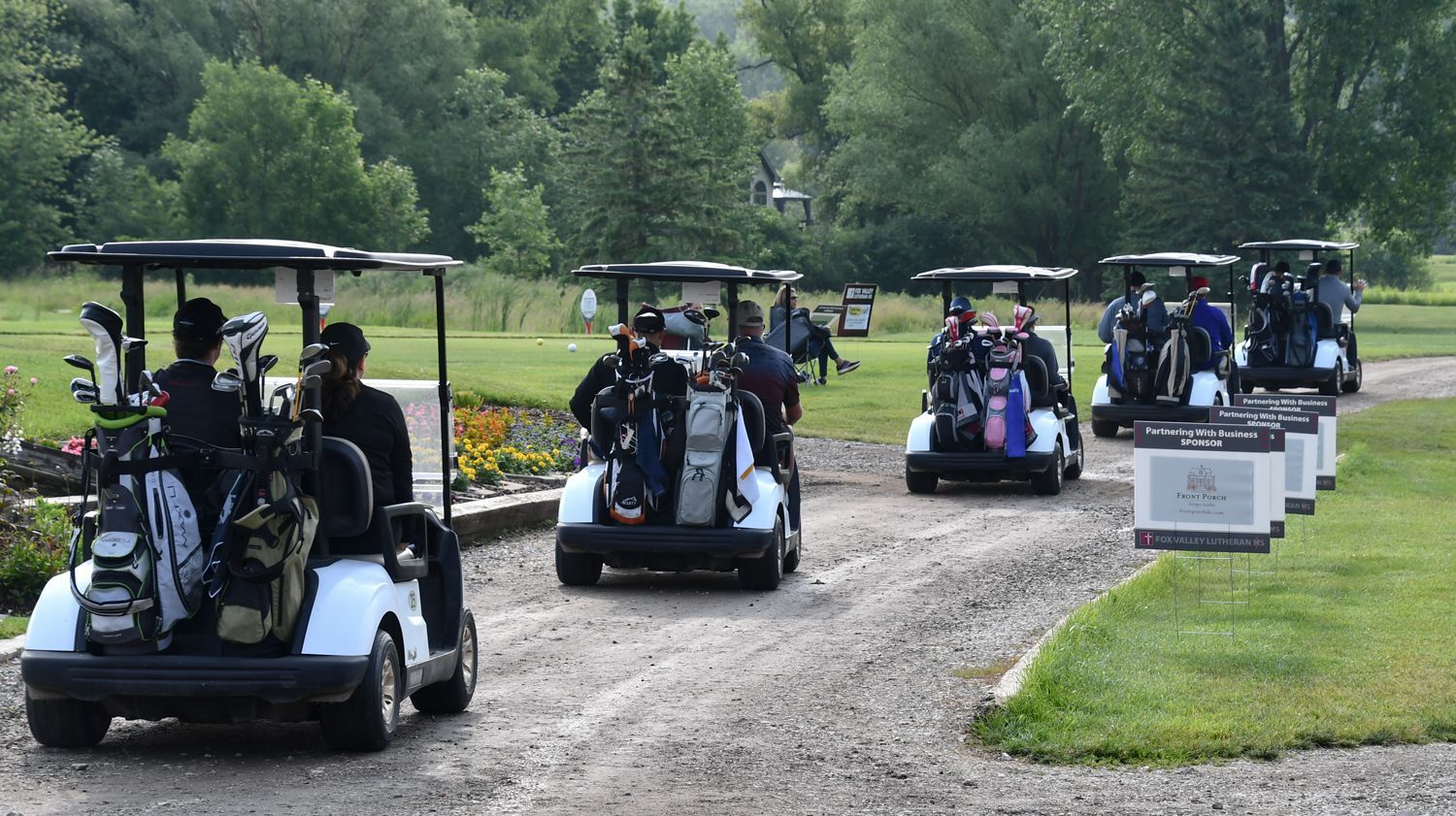 Five golf carts on the way to their holes
