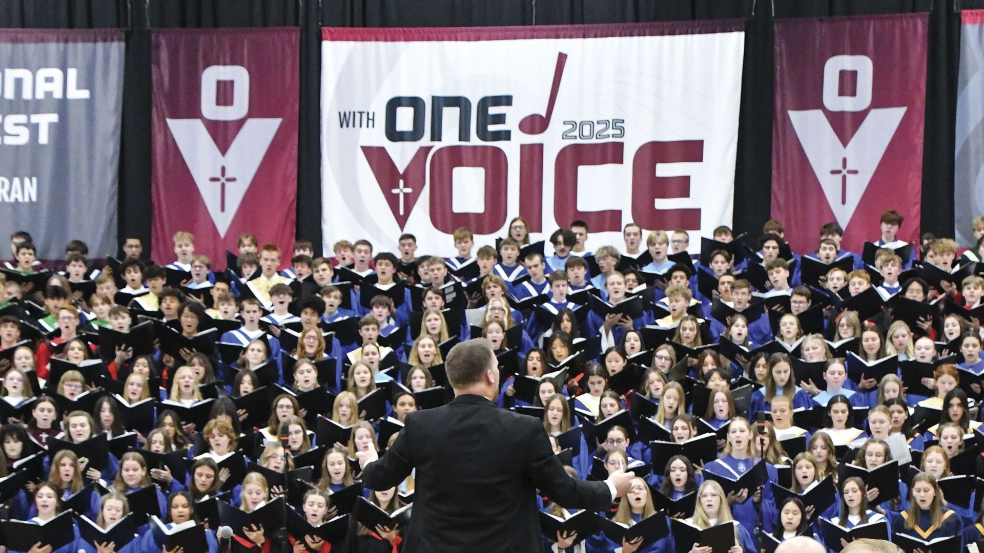 Center portion of the mass choir, singing during the sacred concert, with the event logo behind them