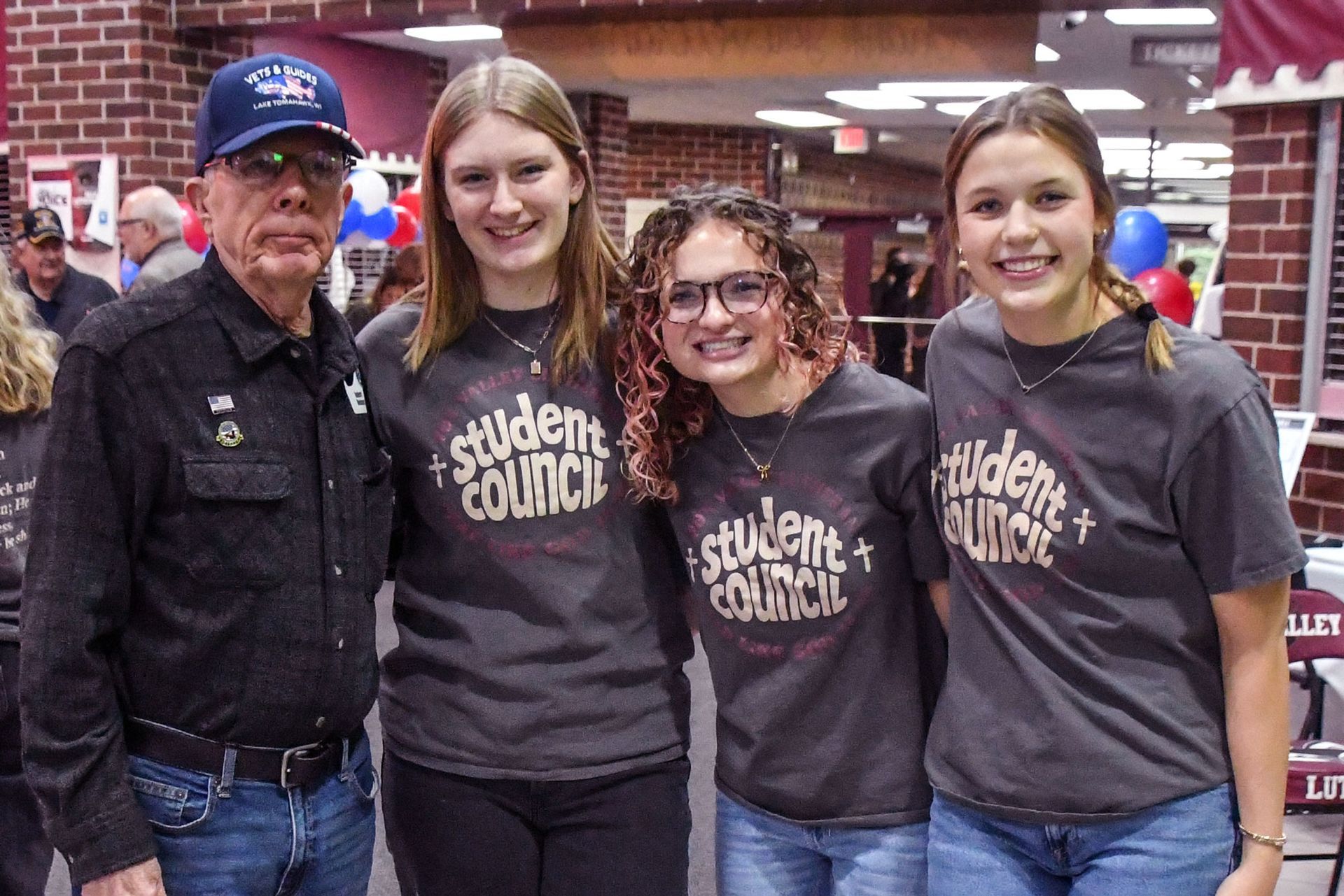 Three smiling students with one smiling veteran.