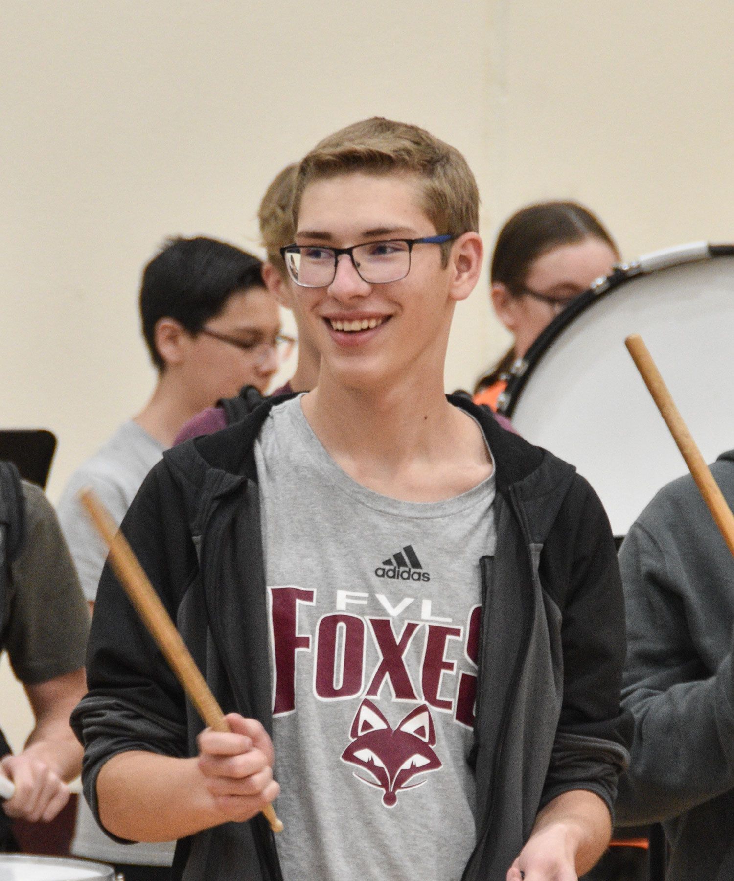 Smiling male student playing cowbell