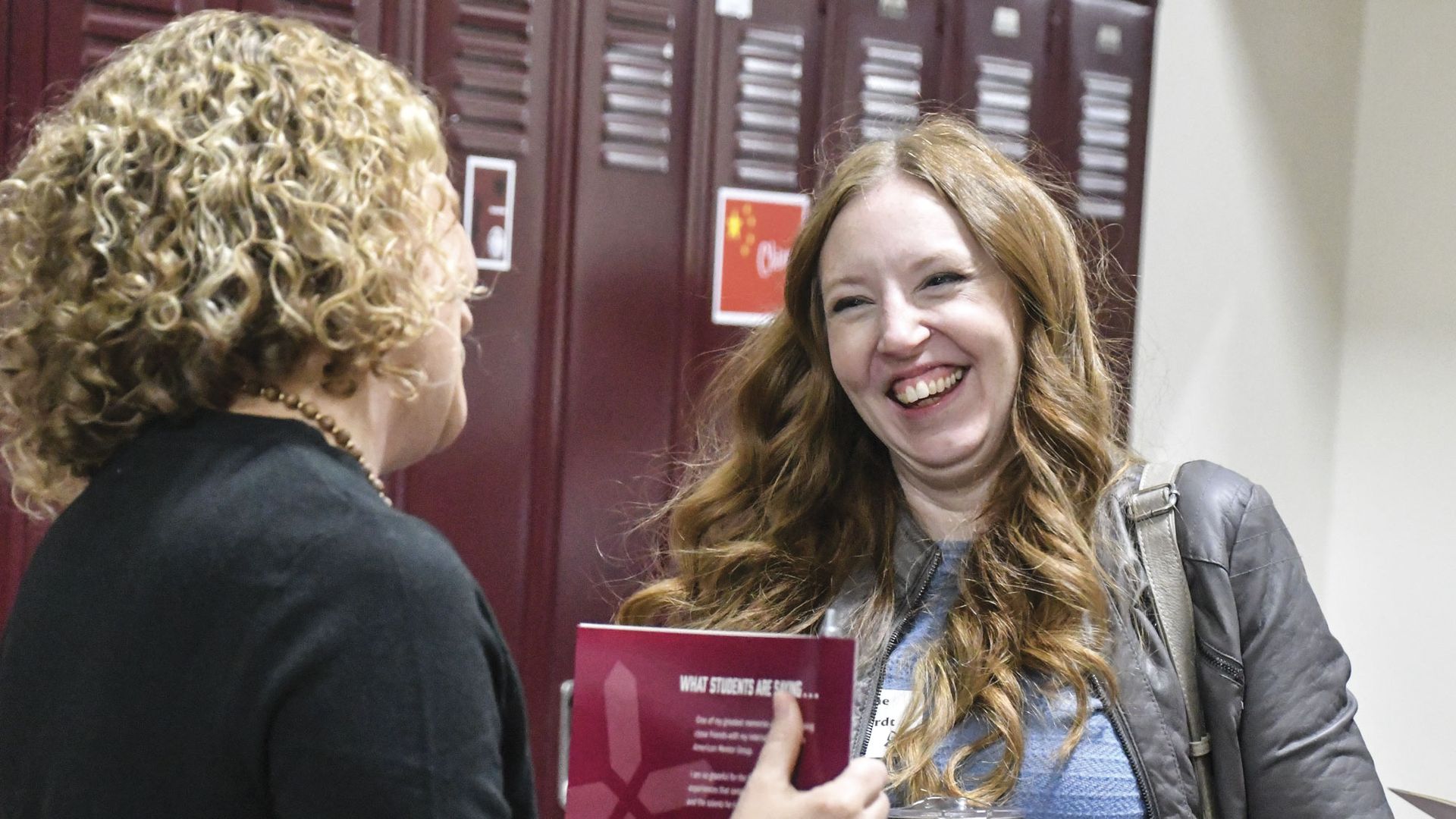A happy parent receiving a folder at 8th Grade Welcome Night