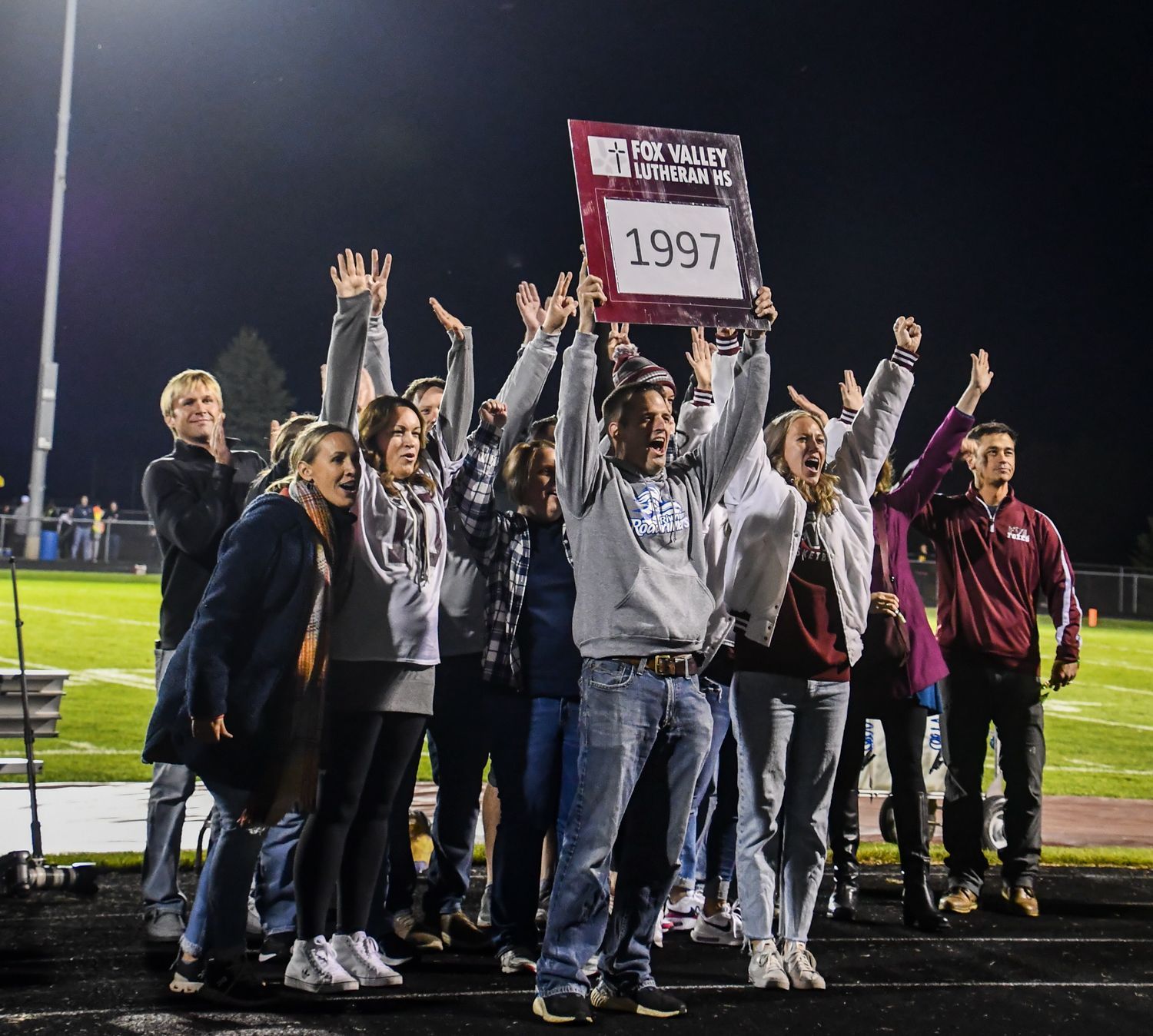 Class of 1997, holding their year sign while standing on the track during halftime recognition at the 2022 Homecoming game