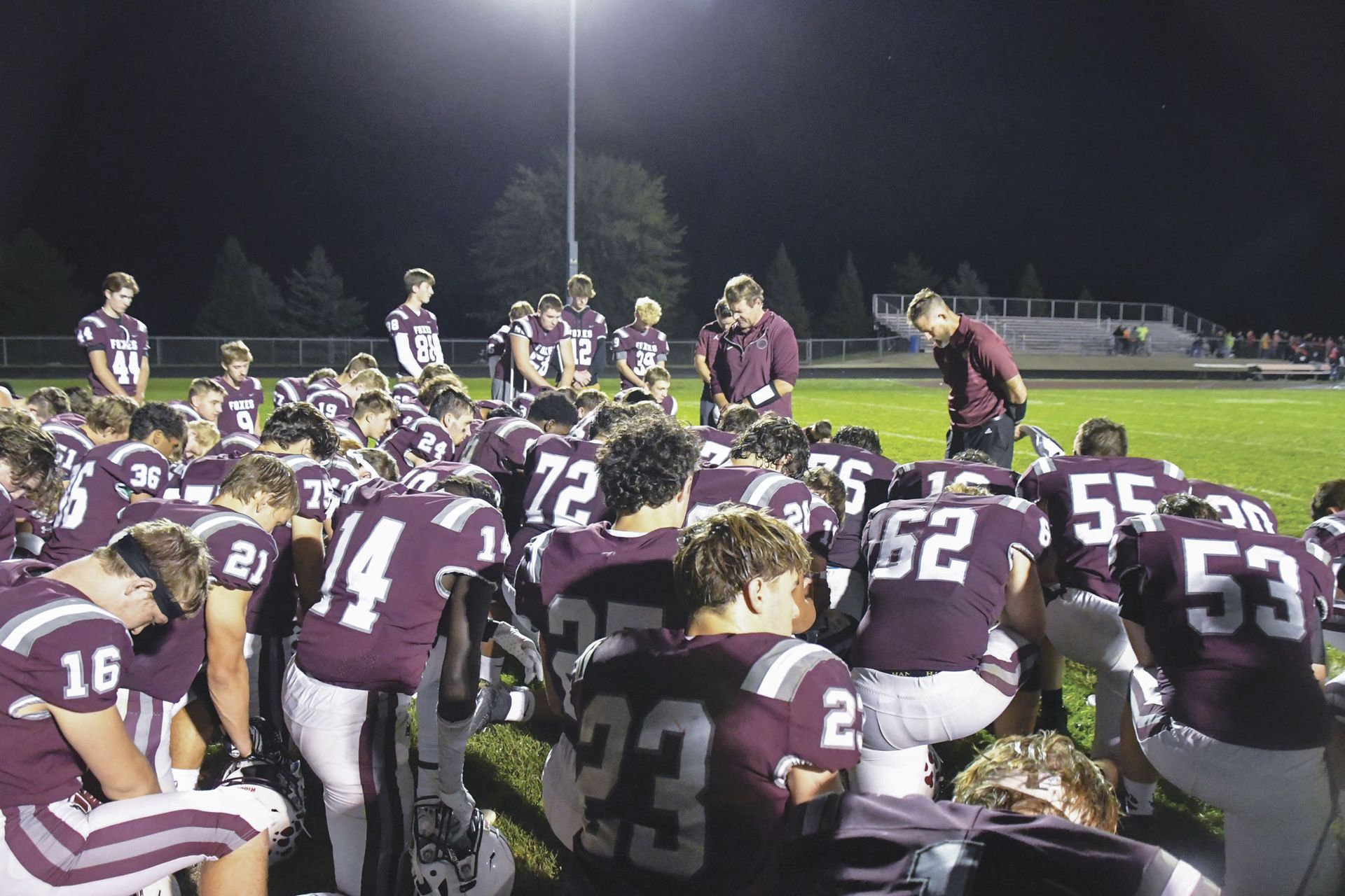 Team kneeling and praying with coaches
