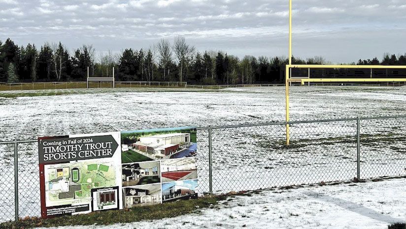 Future location of Trout Center - sign on fence, and snow-covered soccer field