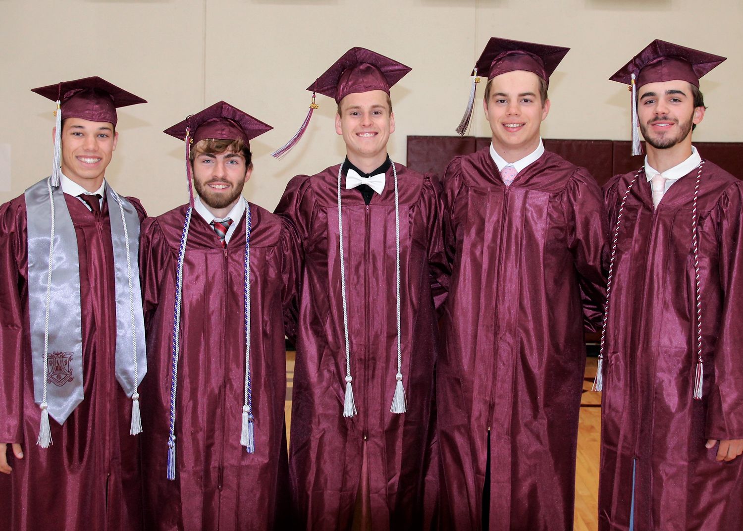 Five guys in caps and gowns, smiling and looking at the camera