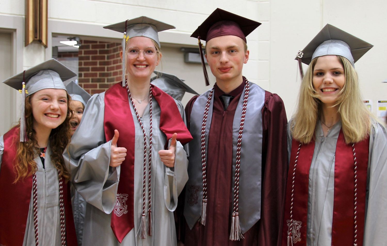 Three girls and one guy, all with stoles and cords, smiling for the camera