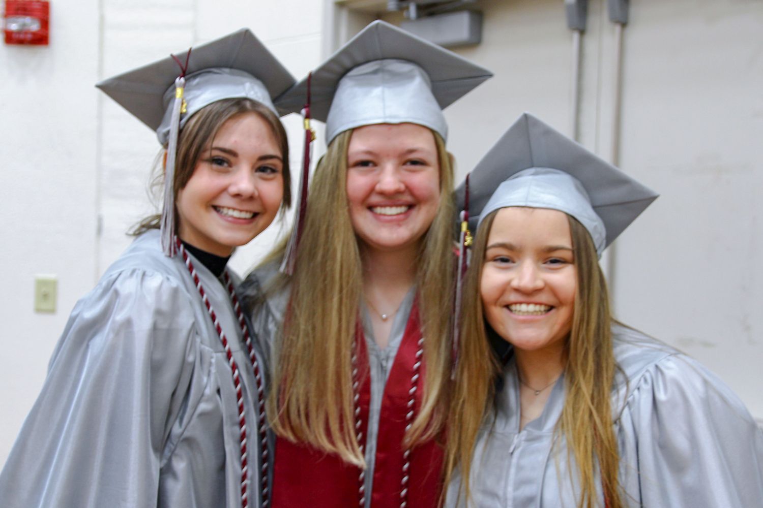 Three smiling girls in caps and gowns