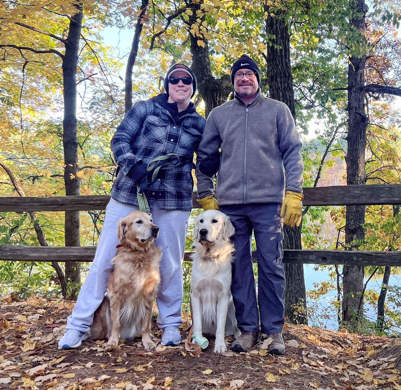 Rachel, her husband, and two dogs on a path in the woods in autumn