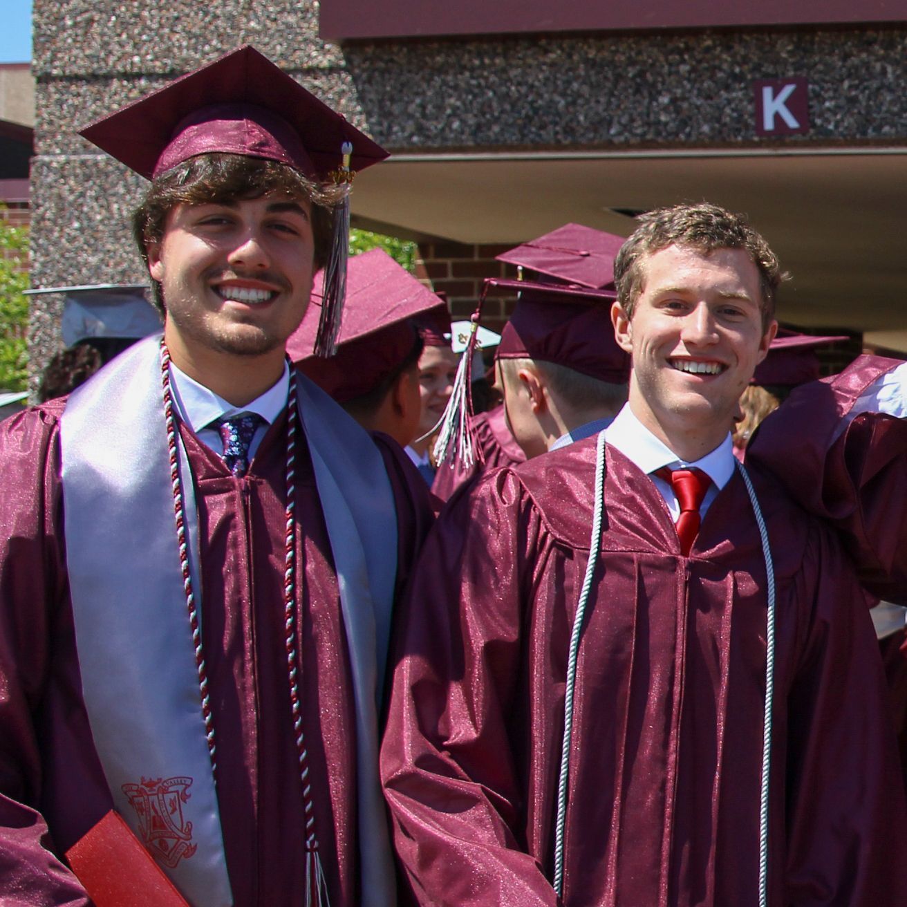 Two guys, smiling for the camera, outside, after graduation