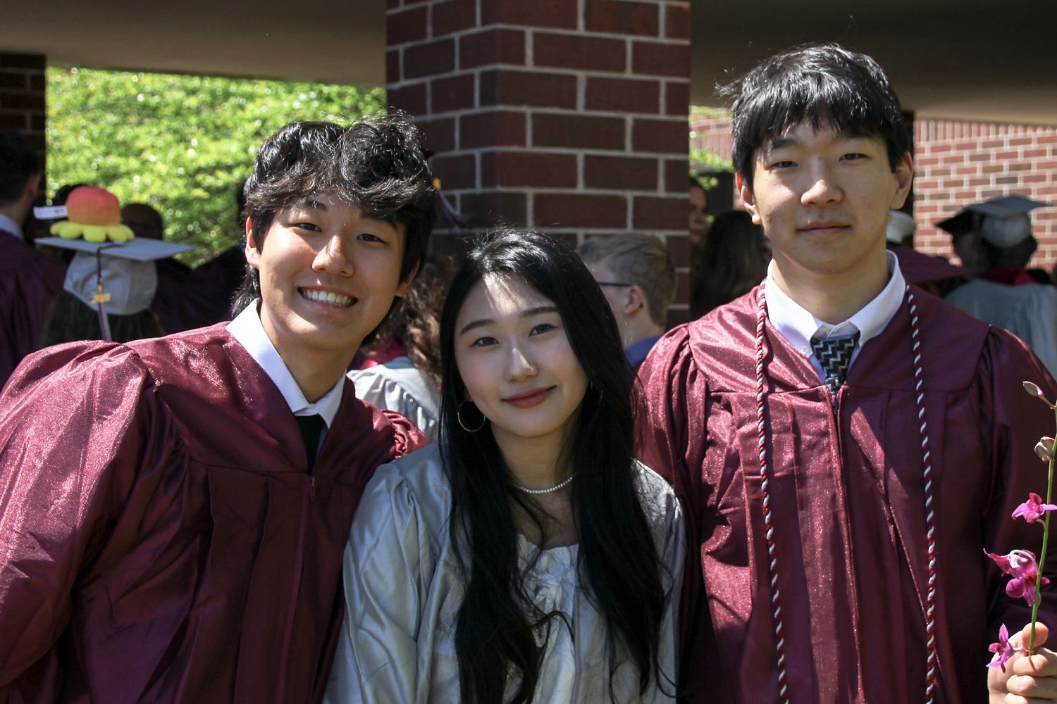 Two guys and a girl, smiling for the camera after the ceremony