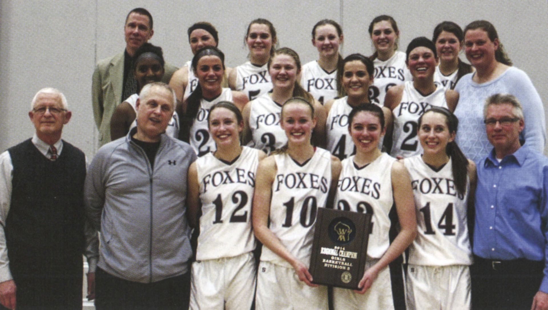 Girls team with coaches, smiling at camera and holding up WIAA winning plaque 