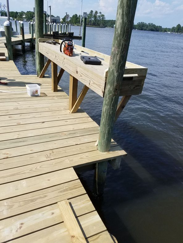 Wooden dock under construction beside a lake, with tools and supports on the deck.
