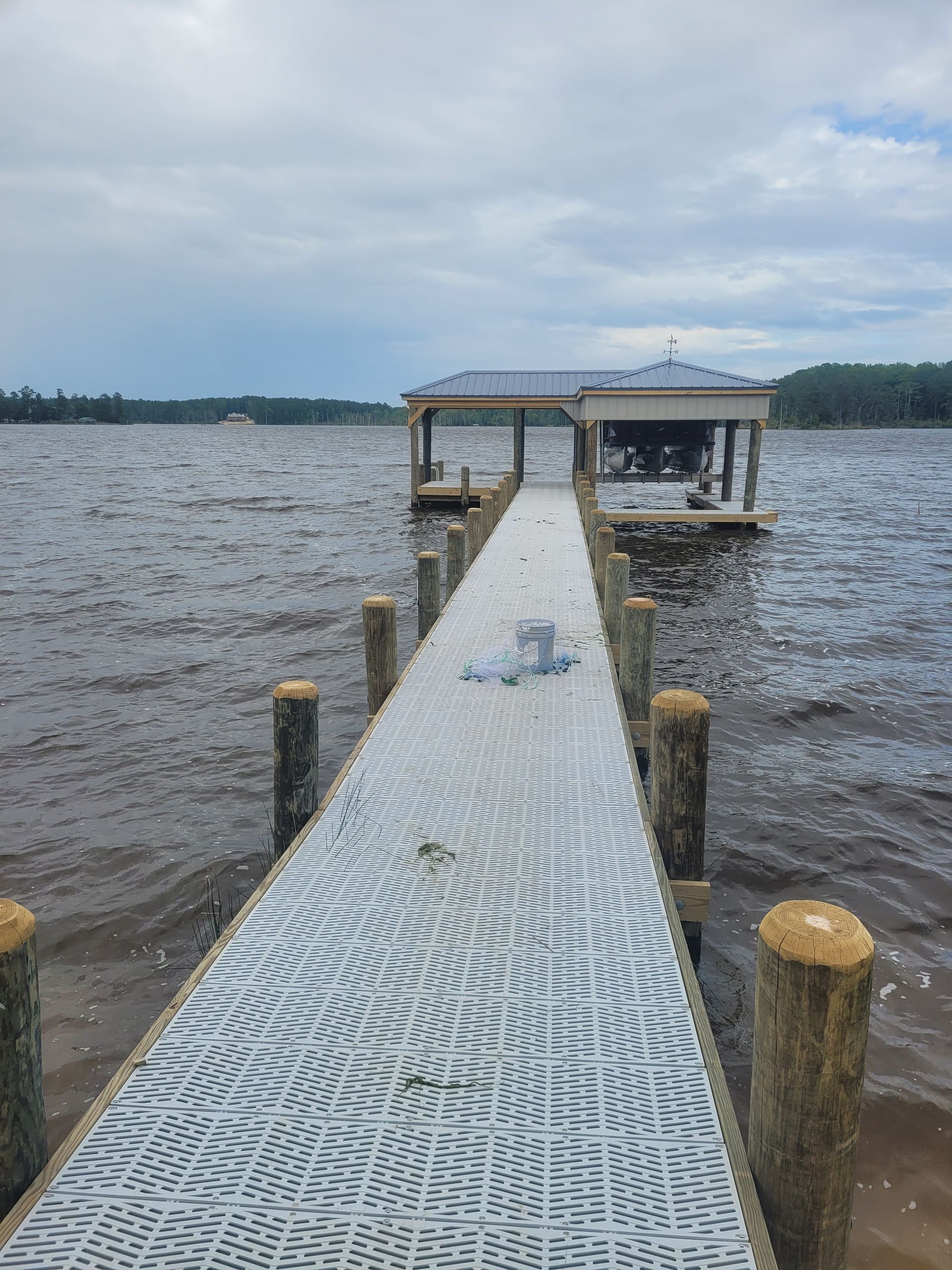 Metal dock leading to a lakeside gazebo under a cloudy sky