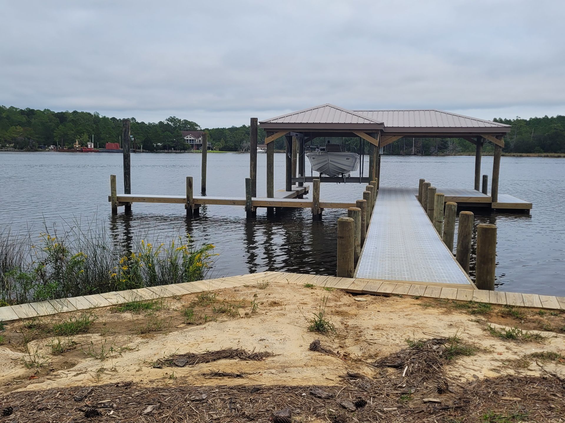 Wooden dock with gazebo extending into a calm lake under an overcast sky