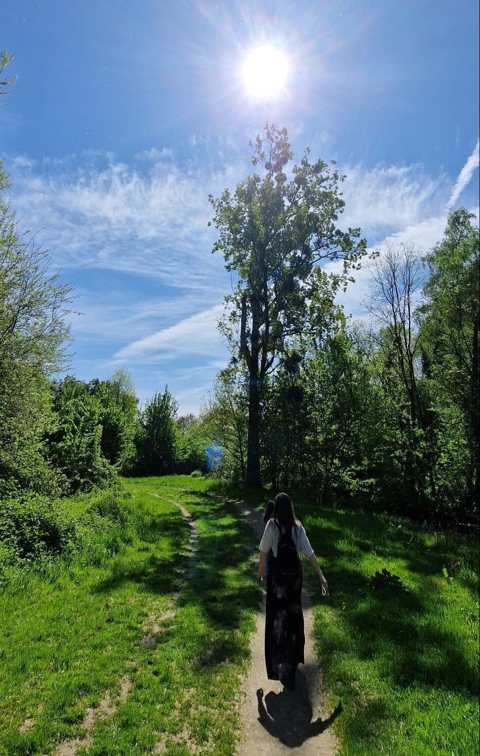 Een vrouw loopt op een zonnige dag over een pad in het bos.