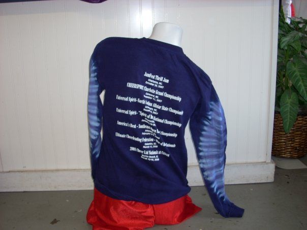 Mannequin wearing a dark blue tie-dye long-sleeve shirt and red shorts. The shirt's back has white text listing achievements.
