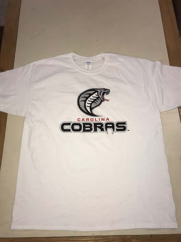 White t-shirt with Carolina Cobras logo; cobra head in black, gray, and red above team name.