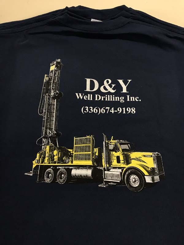 Dark blue t-shirt with a yellow and white logo of a well drilling rig and the compan