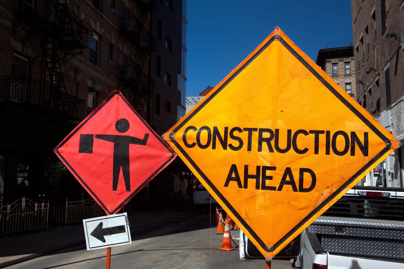 Construction signs on city street: worker with flag, 